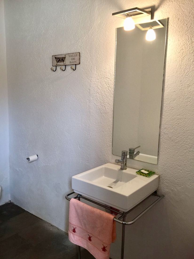 A small guest bathroom with a modern square sink and a pink towel