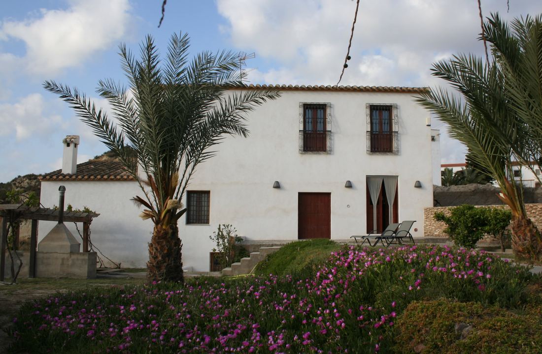 The whitewashed two-storey facade of Molino de Guevara, framed by palm trees