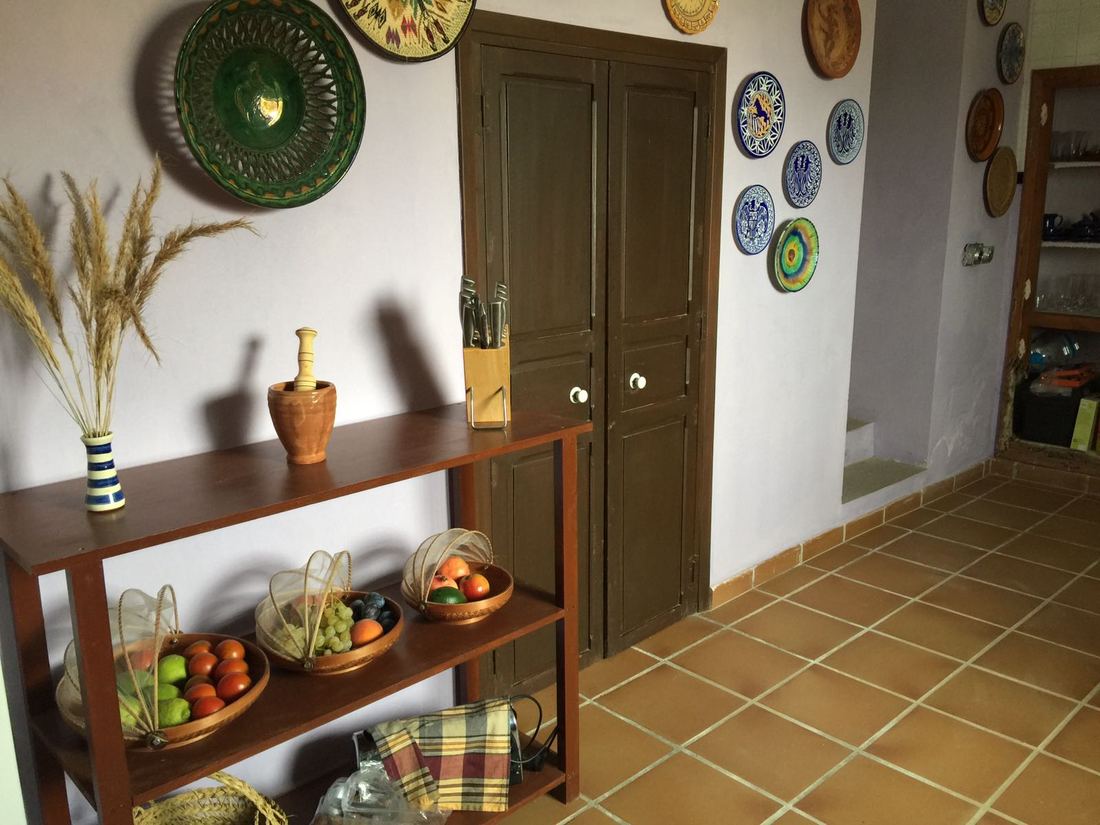 A hallway near the kitchen with a console table, baskets of fruit and decorative ceramic plates on the wall