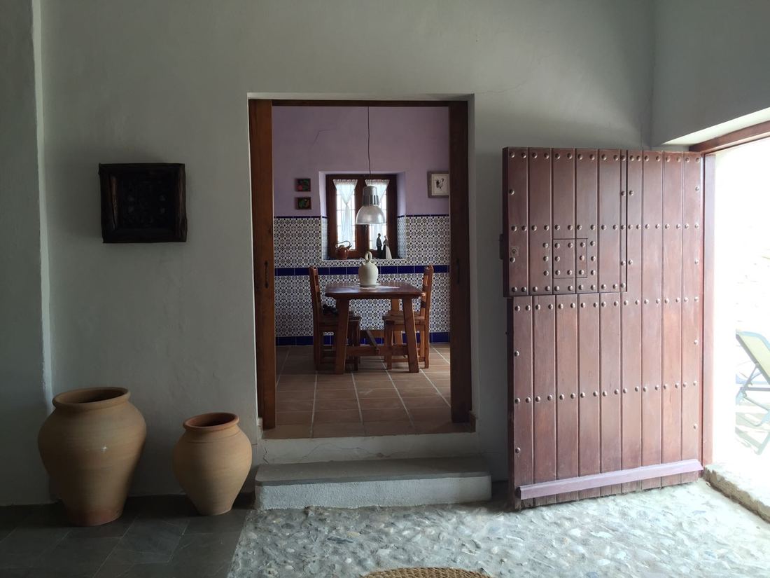 The tiled dining room, seen through an open wooden door, with terracotta jars in the foreground