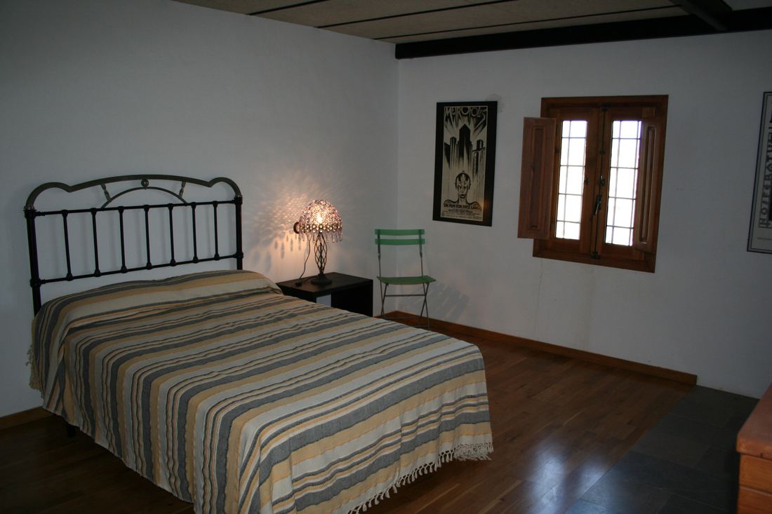 A bedroom with a wrought-iron bed, striped bedspread and a framed vintage film poster