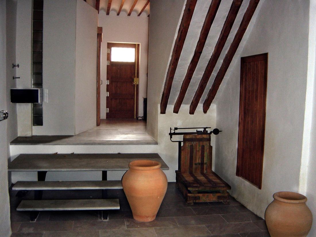 The ground-floor hall near the front door, with a picnic-style table, an antique scale and large terracotta jars