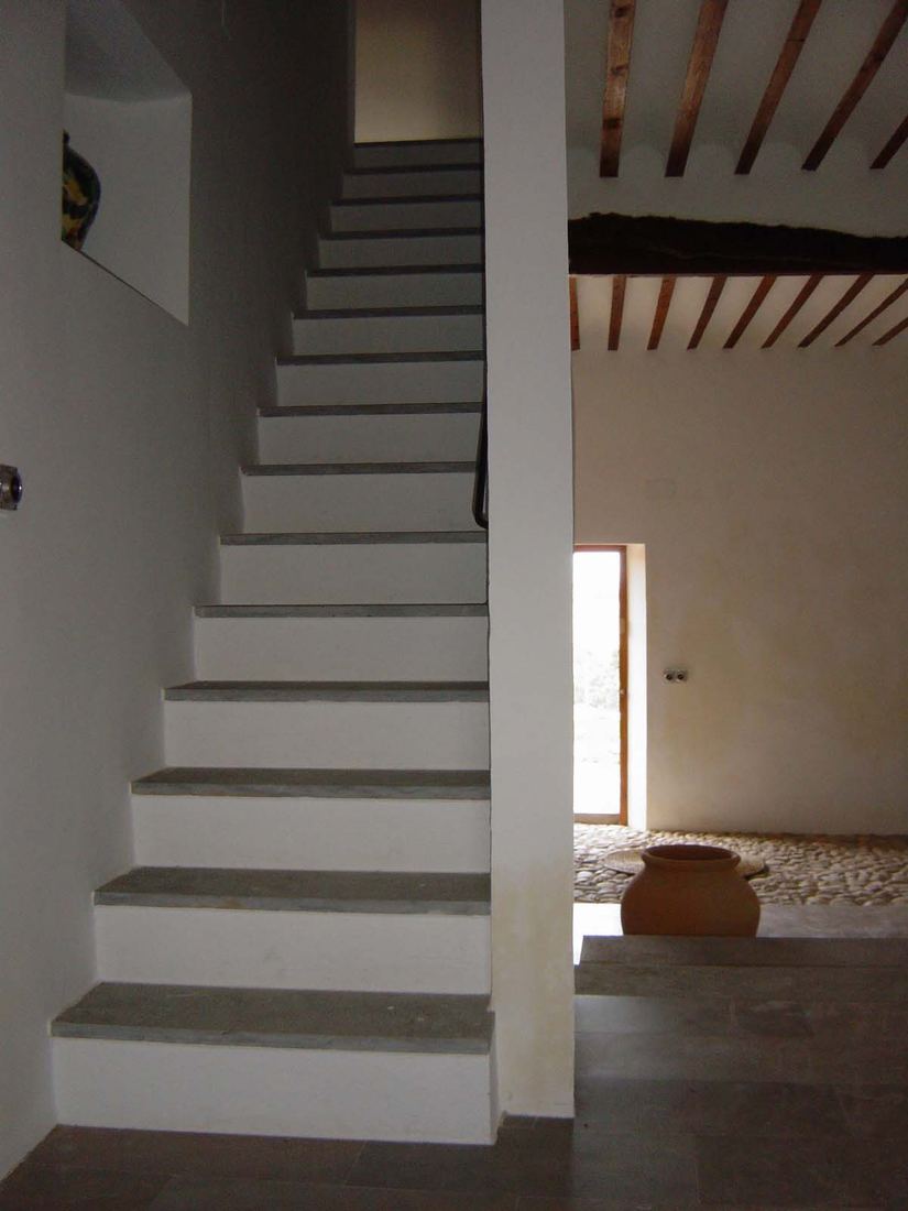 The staircase leading to the first-floor bedrooms, with a terracotta jar at its foot