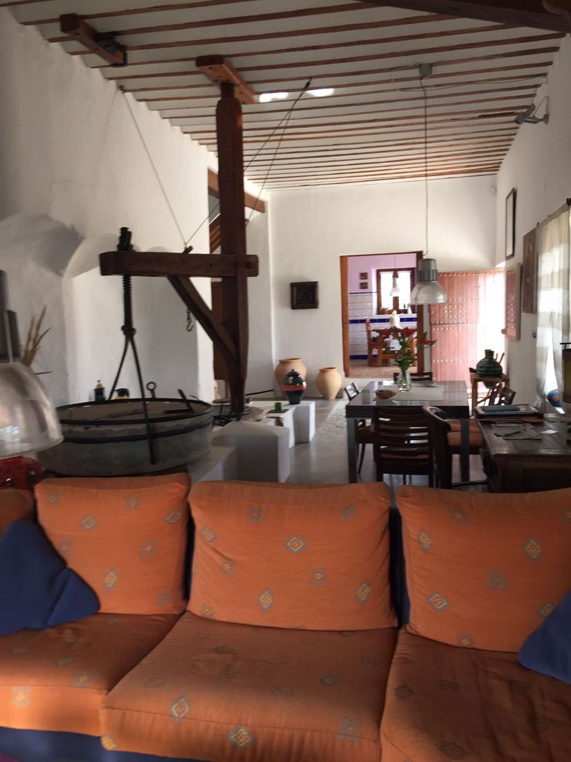 A sofa in the living room looking toward the dining table and the mill's old wooden press